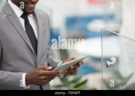 Ritagliato colpo di sorridente imprenditore africano azienda digitale compressa in mani, spazio di copia Foto Stock