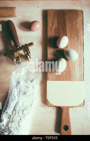 La preparazione della pasta fatta in casa, verde naturale uovo, oliva egger, uova di colore bianco e marrone, Farina e pasta cutter su un sfondo di legno Foto Stock