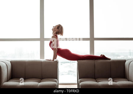 Attraente donna forte nel colore rosso brillante vestito di eseguire lo yoga Foto Stock
