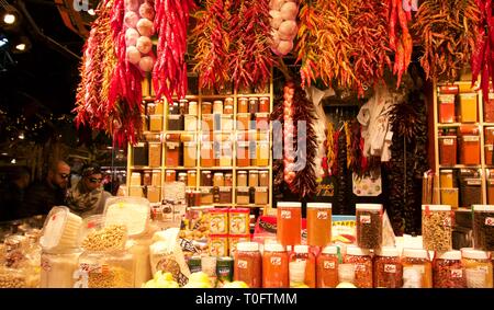 Negozio di gastronomia con stringhe di aglio e peperoncino sul display sopra i contenitori in plastica degli aromi Foto Stock