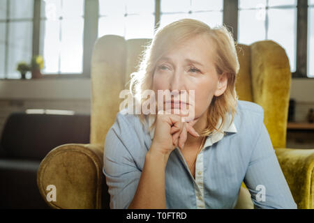 Stanco e turbato donna bionda appoggiando il suo mento Foto Stock