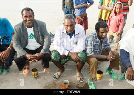 Hamd Ela, Etiopia, 23 Febbraio 2015: uomini etiope sedersi fuori in strada a parlare e bere una bibita locale dal vecchio lattine di lattina Foto Stock