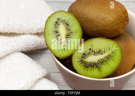 Kiwi le fette su un tavolo di legno accanto ad un asciugamano bianco, close-up Foto Stock