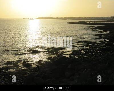 Affacciata sul mare, di sera presto in Lanzarote, quando il sole al tramonto proietta un bagliore giallo sull'acqua Foto Stock