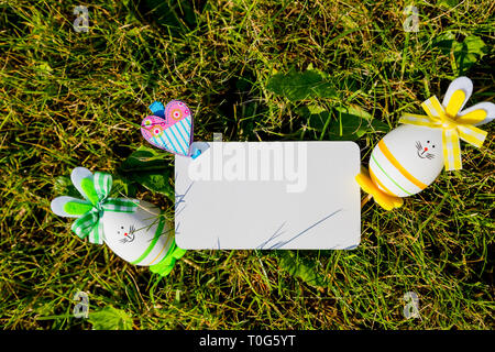 Bigliettino vuoto con piccole uova di pasqua in erba.le uova di Pasqua su prato. Vacanze di primavera concetto .composizione di Pasqua con le uova di pasqua .Mockup Foto Stock