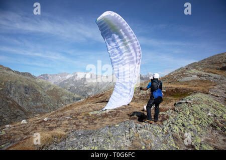 Giovane pilota di parapendio utilizza il suo parapendio a giocare con il vento nelle alpi svizzere, il cosiddetto trattamento di massa Foto Stock