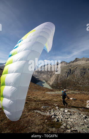 Giovane pilota di parapendio utilizza il suo parapendio a giocare con il vento nelle alpi svizzere, il cosiddetto trattamento di massa Foto Stock