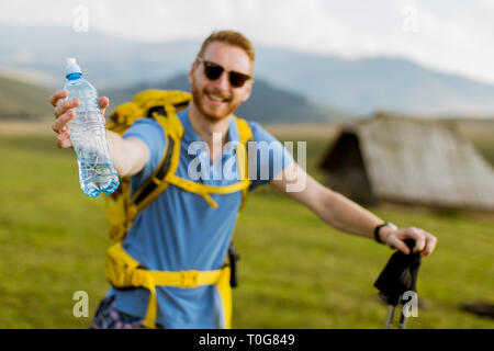 Giovane bello escursionista arrestato e bere acqua da una bottiglia Foto Stock