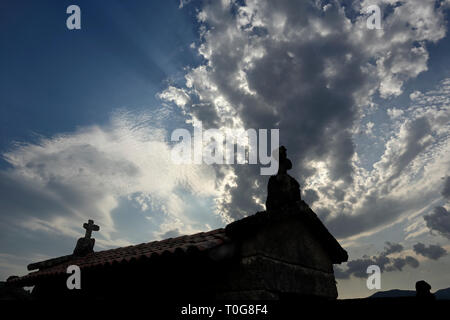 Lindoso centennial fienile di granito con la sua caratteristica di croci sulla parte superiore contro un cielo drammatico, il nord del Portogallo. Soft retroilluminati. Foto Stock