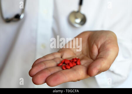 Terapista presso l'ambulatorio medico con red pillole, uomo con uno stetoscopio dando farmaco in capsule. Concetto di prescrizione medica, la dose dei farmaci Foto Stock