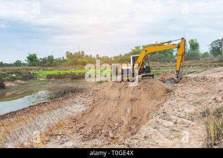 Escavatore giallo di lavoro della macchina movimento terra che lavora al sito in costruzione Foto Stock