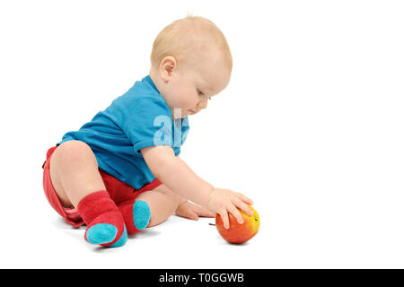 Ragazzino con un Apple seduto su sfondo bianco, isolato Foto Stock