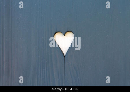 Forma di cuore tagliato sul grigio telo in legno vicino. Foto Stock