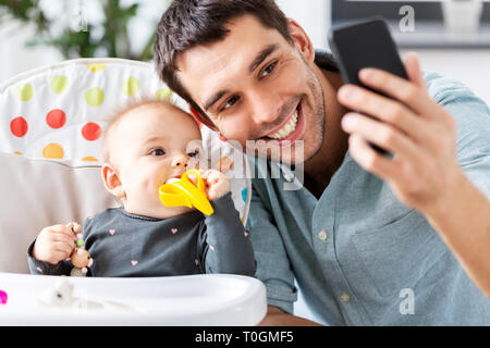 Padre con la nostra bambina tenendo selfie a casa Foto Stock