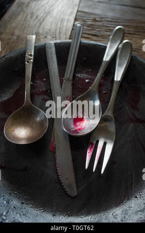 Argenteria sporco su una piastra sporchi coperti con salsa di mirtilli dopo un pasto Foto Stock