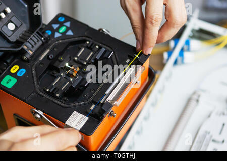 Lavoratore di comunicare il cavo a fibra ottica a opto box. l'installazione di nuove apparecchiature di rete. Foto Stock