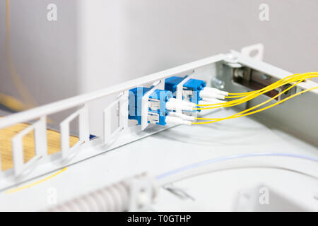 Lavoratore di comunicare il cavo a fibra ottica a opto box. l'installazione di nuove apparecchiature di rete. Foto Stock