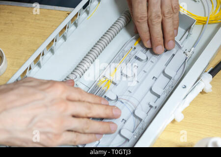 Lavoratore di comunicare il cavo a fibra ottica a opto box. l'installazione di nuove apparecchiature di rete. Foto Stock