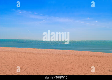 Faro, Portogallo. Una generica spiaggia, con sabbia dorata, mare scintillante, uno yacht o due sullo sfondo e un bel cielo blu. Foto Stock
