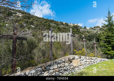 Questa è una acquisizione per un multiplo croci cristiane che siedono su un muro di pietra con una foresta verde sullo sfondo Foto Stock