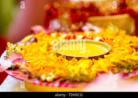 A Haldi tradizionale curcuma mantenuta su una piastra di fiori per il matrimonio indù cerimonia Foto Stock
