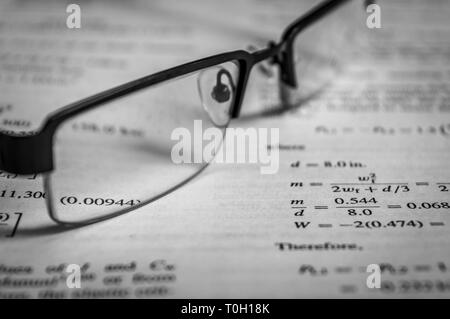 Occhiali mantenuta su un libro dopo la lettura Foto Stock