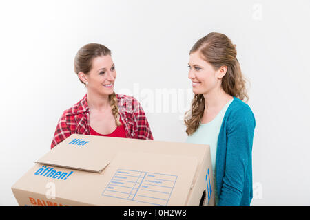 Sorridere le donne che trasportano la scatola di cartone Foto Stock