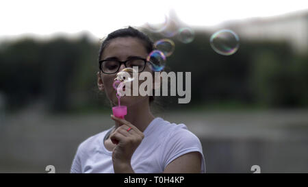 Ragazza in bicchieri soffia bolle in slow motion, divertirsi Foto Stock