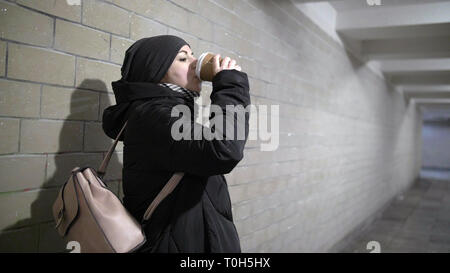 Pretty Woman beve caffè in un tunnel, pensa a qualcosa di qualcuno è in attesa di Foto Stock