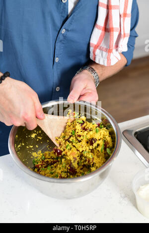Cibo uomo facendo un couscous piatto di insalata in una cucina domestica Foto Stock