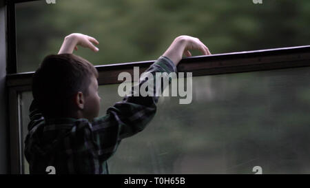 Felice ragazzo è il viaggio in treno di sera, guardando fuori dalla finestra Foto Stock