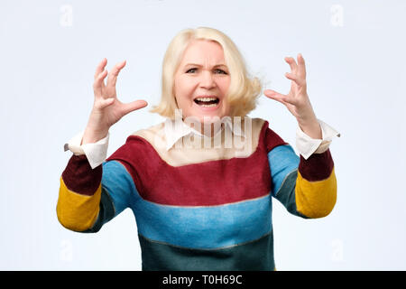 Arrabbiato vecchia donna rendendo Viso arrabbiato gesto su sfondo bianco Foto Stock