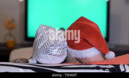 Uomo con una donna in cappelli di Natale guardando la TV, il chroma key Foto Stock