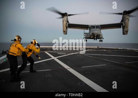 Oceano Pacifico (16 marzo 2019) - Aviazione di Boatswain Mate (manipolazione) Airman Brian Bickmeier dirige lo sbarco di una MV-22B Osprey dal mezzo marino Tiltrotor Squadron 164 sul ponte di volo della USS New Orleans (LPD 18) durante l'esercizio pacifico Blitz 19. Pacific Blitz è uno scenario-driven esercizio congiunto che fornisce corsi di formazione pertinenti dalla replica di una realistica minaccia marittima ambiente concepito per stimolare e migliorare la capacità anfibie necessaria per una effettiva crisi globale risposta. (U.S. Foto di Marina di Massa lo specialista di comunicazione 2a classe Kelby Sanders) Foto Stock