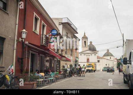 La strada con negozi, pizzeria, bar, caffe, la chiesa, in una piccola città sull isola di Sardegna, Italia Foto Stock