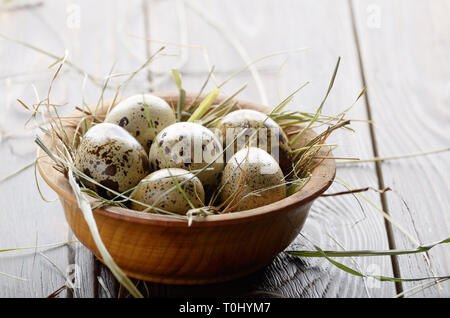 Organico fresco uova di quaglia in ciotola di legno rustico tavolo da cucina. Spazio per il testo Foto Stock