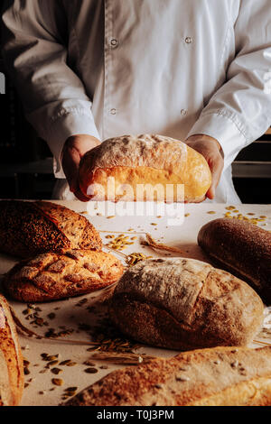 Professional baker che mostra i diversi tipi di pasta di pane cotto al forno Foto Stock