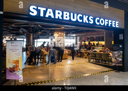 I viaggiatori agguantare un veloce caffè di Starbucks cafe lounge in l'aeroporto di KL Foto Stock