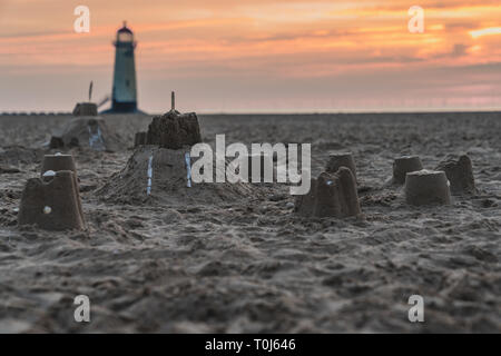 Il Sandcastles On la spiaggia, con serata nuvole e punto di Ayr il faro in background, vicino Talacre, Flintshire, Wales, Regno Unito Foto Stock