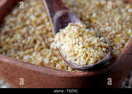 Non cotti materie Bulgur di grano grani nella ciotola di legno Foto Stock