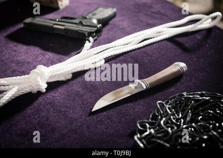 Pistola, coltello, fune, catena, pistola alla scena del crimine sul tavolo, segnalazioni di reati, foto a ISO elevata Foto Stock