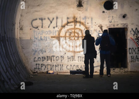La troupe cinematografica spara la trama in una stanza abbandonata dipinto graffiti, video presso la scena del crimine in un bunker abbandonati Foto Stock