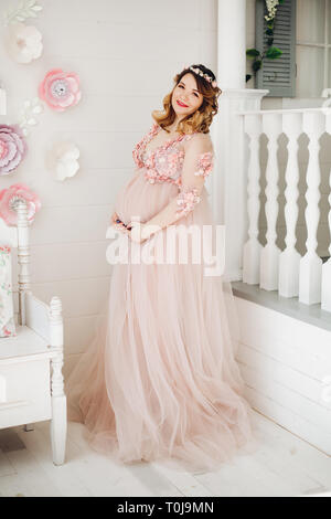 Elegante futura madre in posa lungo abito in polvere. Foto Stock