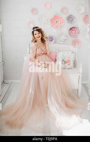 Elegante futura madre in posa lungo abito in polvere. Foto Stock