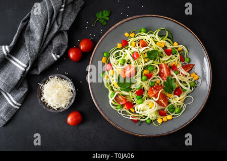 Zoodlie, sano cibo vegan - zucchine noodlie con fresco verde piselli, pomodoro, peperone e mais per il pranzo, vista da sopra Foto Stock