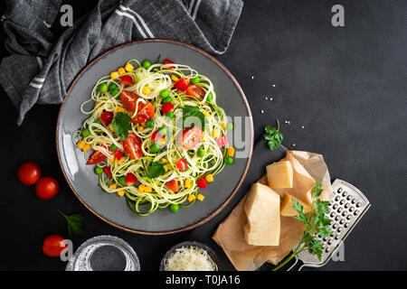 Zoodlie, sano cibo vegan - zucchine noodlie con fresco verde piselli, pomodoro, peperone e mais per il pranzo, vista da sopra Foto Stock