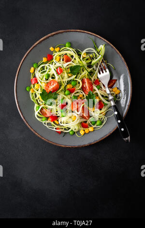 Zoodlie, sano cibo vegan - zucchine noodlie con fresco verde piselli, pomodoro, peperone e mais per il pranzo, vista da sopra Foto Stock