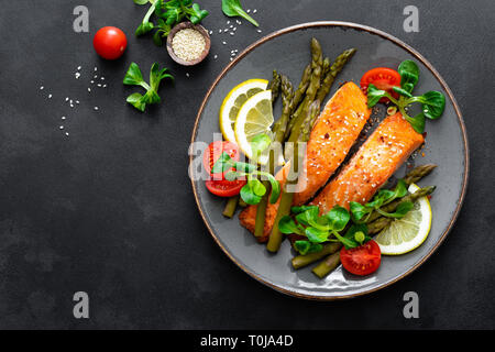 Salmone alla griglia bistecca di pesce, asparagi, pomodoro e insalata di mais sulla piastra. Piatto sano per il pranzo. Vista superiore Foto Stock