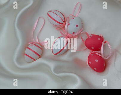 Rosa e Bianco uova di pasqua su un lucido sfondo tessili Foto Stock