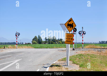 Incrocio ferroviario nella regione di Canterbury della Nuova Zelanda. Paese senza attraversamento di cancelli o barriera. Guardare per treni segno. Motore a vapore graphic Foto Stock